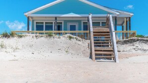 Una casa de playa con una escalera de madera que lleva a un porche.