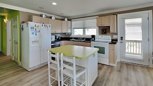 Una cocina compacta con una isla central, un refrigerador, una estufa y un lavaplatos.