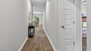 A hallway with a wooden floor, white walls, and a white door. -   New Construction!!! Sleeps 7! Short drive to Sunset &Ocean Isle Beach / Golf!! (Sunset Beach)