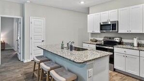 A modern kitchen with white cabinets, a granite countertop, a built-in oven, and a stainless steel microwave. -   New Construction!!! Sleeps 7! Short drive to Sunset &Ocean Isle Beach / Golf!! (Sunset Beach)