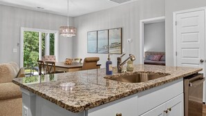 A modern kitchen with a granite countertop, stainless steel sink, and a pendant light. -   New Construction!!! Sleeps 7! Short drive to Sunset &Ocean Isle Beach / Golf!! (Sunset Beach)