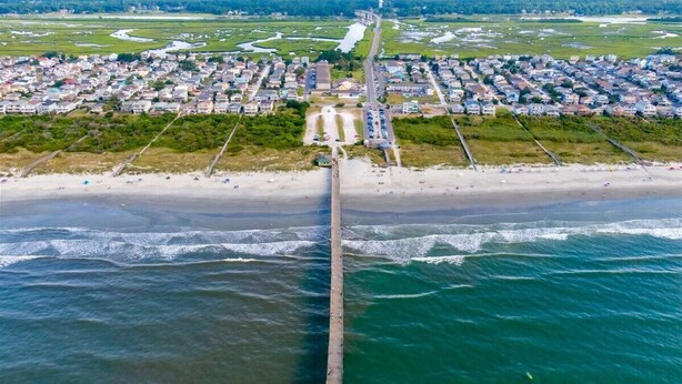 An aerial view of a coastal town with a long pier extending into the sea, surrounded by residential buildings and a beach. -   New Construction!!! Sleeps 7! Short drive to Sunset &Ocean Isle Beach / Golf!! (Sunset Beach)