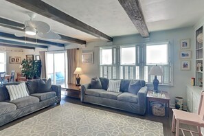 A living room with two grey sofas, a patterned rug, and a ceiling fan.