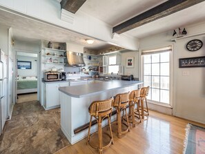 A spacious kitchen with a large island, white cabinetry, and a rustic ceiling. - S.O.B. (Sweet Ol' Bill) by Topsail Realty (Holly Ridge)