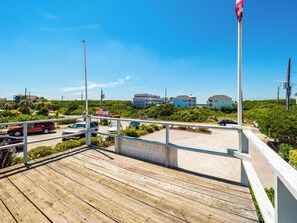 A wooden deck with a view of a parking area and buildings in the background. - S.O.B. (Sweet Ol' Bill) by Topsail Realty (Holly Ridge)