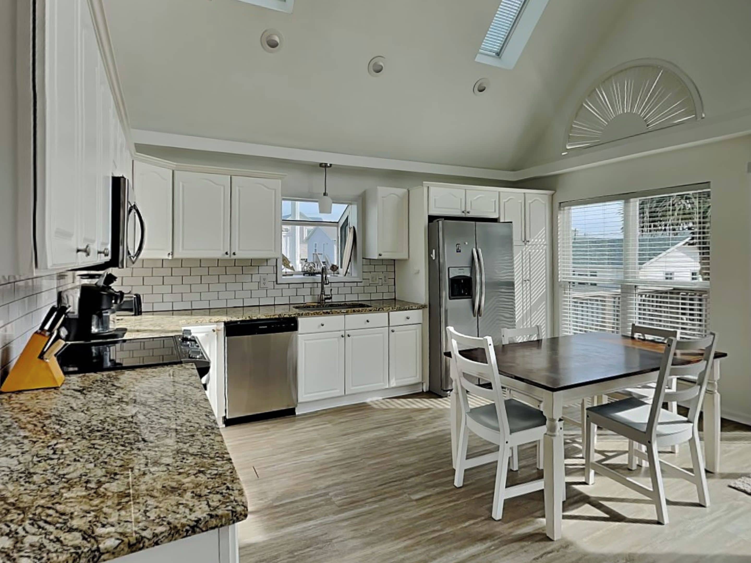 A modern kitchen with white cabinets, a granite countertop, and a built-in dishwasher.