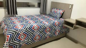 Ein Schlafzimmer mit Bett, Nachttisch und einem Fenster mit Vorhängen.