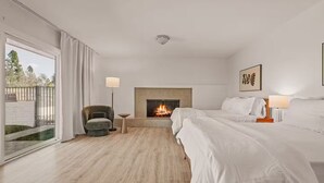 A hotel room with a fireplace, two beds, a chair, and a view of the outdoors. - 5BR Fun Haven: Pool, Mini Golf, Movie, Gameroom (Riverside)