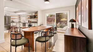 A modern kitchen with white cabinets, a central island, and bar stools. - 5BR Fun Haven: Pool, Mini Golf, Movie, Gameroom (Riverside)