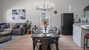 A modern kitchen with a black refrigerator, white cabinets, and a dining area with a table set for six. - Generous 4BR 3BA Charmer Near Glorius Downtown (San Antonio)