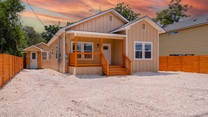 A two-story house with a covered porch and a wooden staircase. - Generous 4BR 3BA Charmer Near Glorius Downtown (San Antonio)