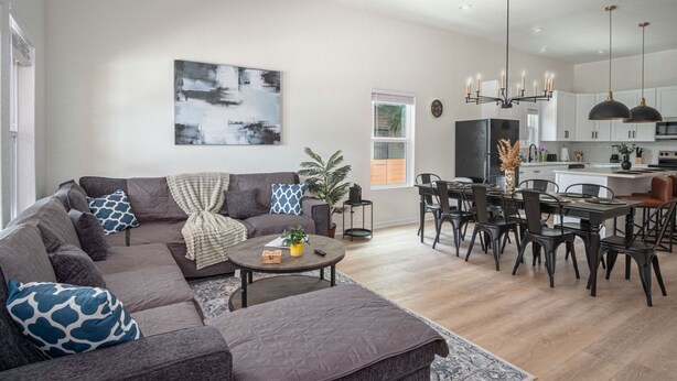 A modern living room with a sectional sofa, a round coffee table, and a dining area with a table and chairs. - Generous 4BR 3BA Charmer Near Glorius Downtown (San Antonio)