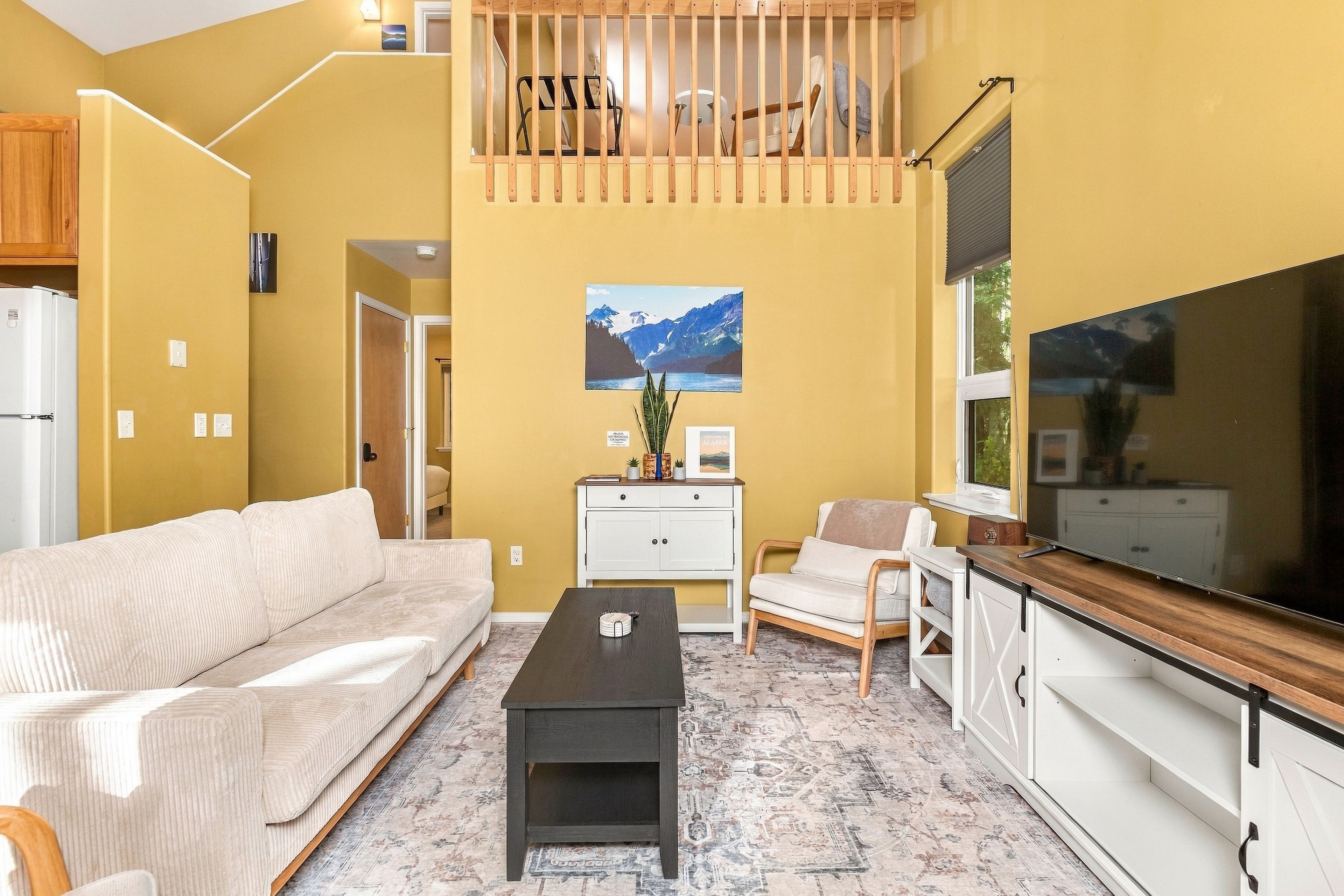 A living room with a sofa, coffee table, TV, and a painting on the wall.