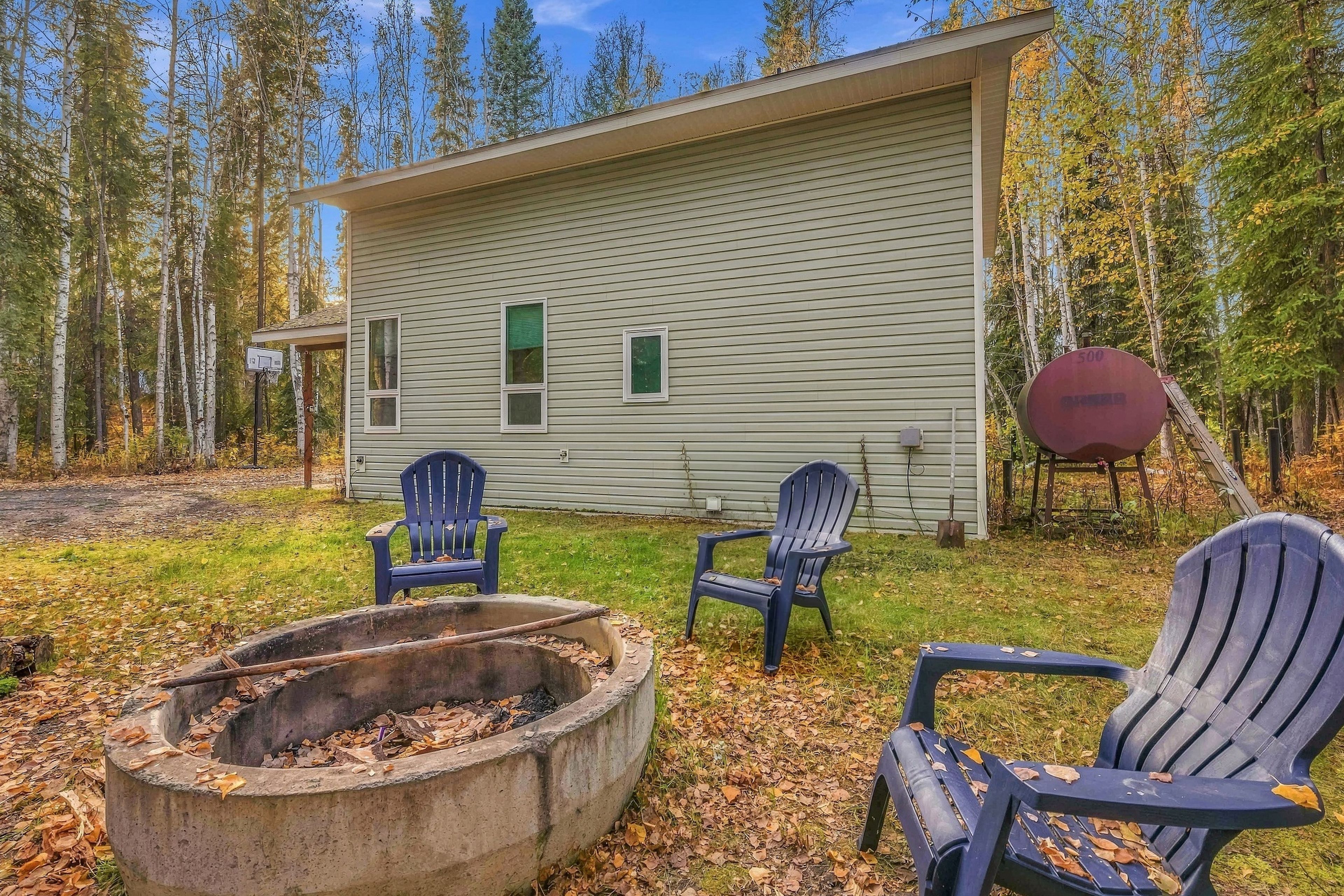 A cabin with a fire pit and Adirondack chairs in the yard.