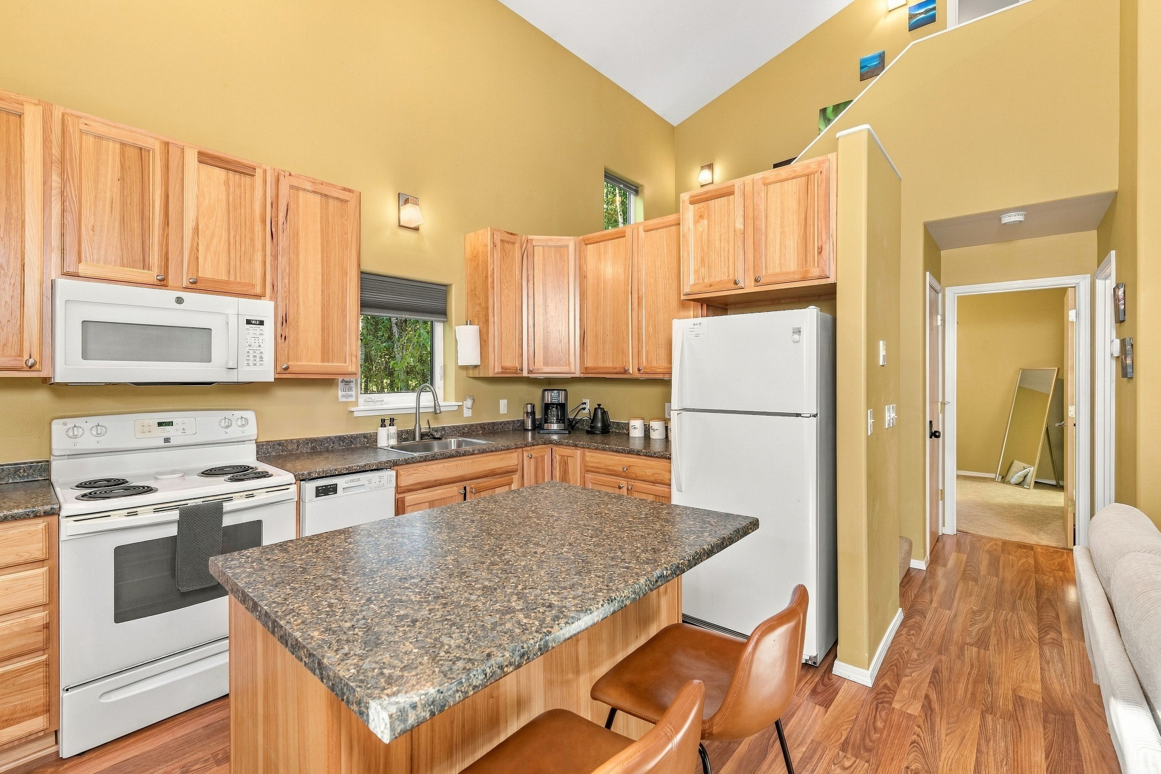 A kitchen with wooden cabinets, a white stove, a microwave, and a refrigerator.