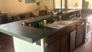A spacious kitchen with a large island, wooden ceiling beams, and a view of the outdoors through large windows. - Charming 3-bedroom Ski Cabin on Golf Course in lovely Incline Village (Incline Village)