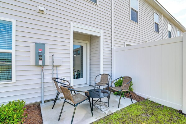 A patio with two wicker chairs and a small table, a utility box, and a white fence. - 2 Mi to Shore: Newly Built Surfside Beach Gem (Surfside Beach)