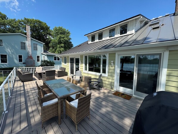 A covered deck with outdoor furniture and a glass enclosure. - Riverfront Oasis with Fun + Relaxation for All, McHenry (McHenry)