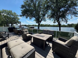 A deck with outdoor furniture, a grill, and a view of a lake. - Riverfront Oasis with Fun + Relaxation for All, McHenry (McHenry)