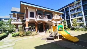 A hotel with a two-story structure, a covered entrance, and a playground with a yellow slide.