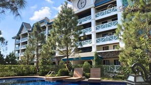 A hotel with a pool area, multiple balconies, and a clock tower.