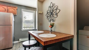 Een keuken met een houten tafel, twee krukken, een koelkast en een decoratief wandobject.