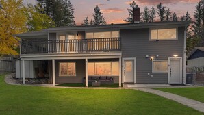 A two-story house with a balcony, a covered porch, and a well-maintained lawn. - Private Studio/1 Min-Hospital/Self Check-In/75" TV (Williams Lake)