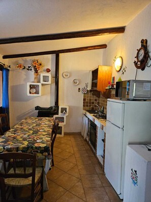 Une cuisine compacte comprenant une table à manger, des chaises, un réfrigérateur, un four à micro-ondes et une horloge murale.