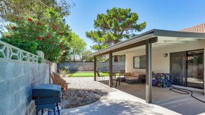 Un patio couvert aménagé avec du mobilier d’extérieur, un barbecue et un espace au bord de la piscine avec des chaises longues.