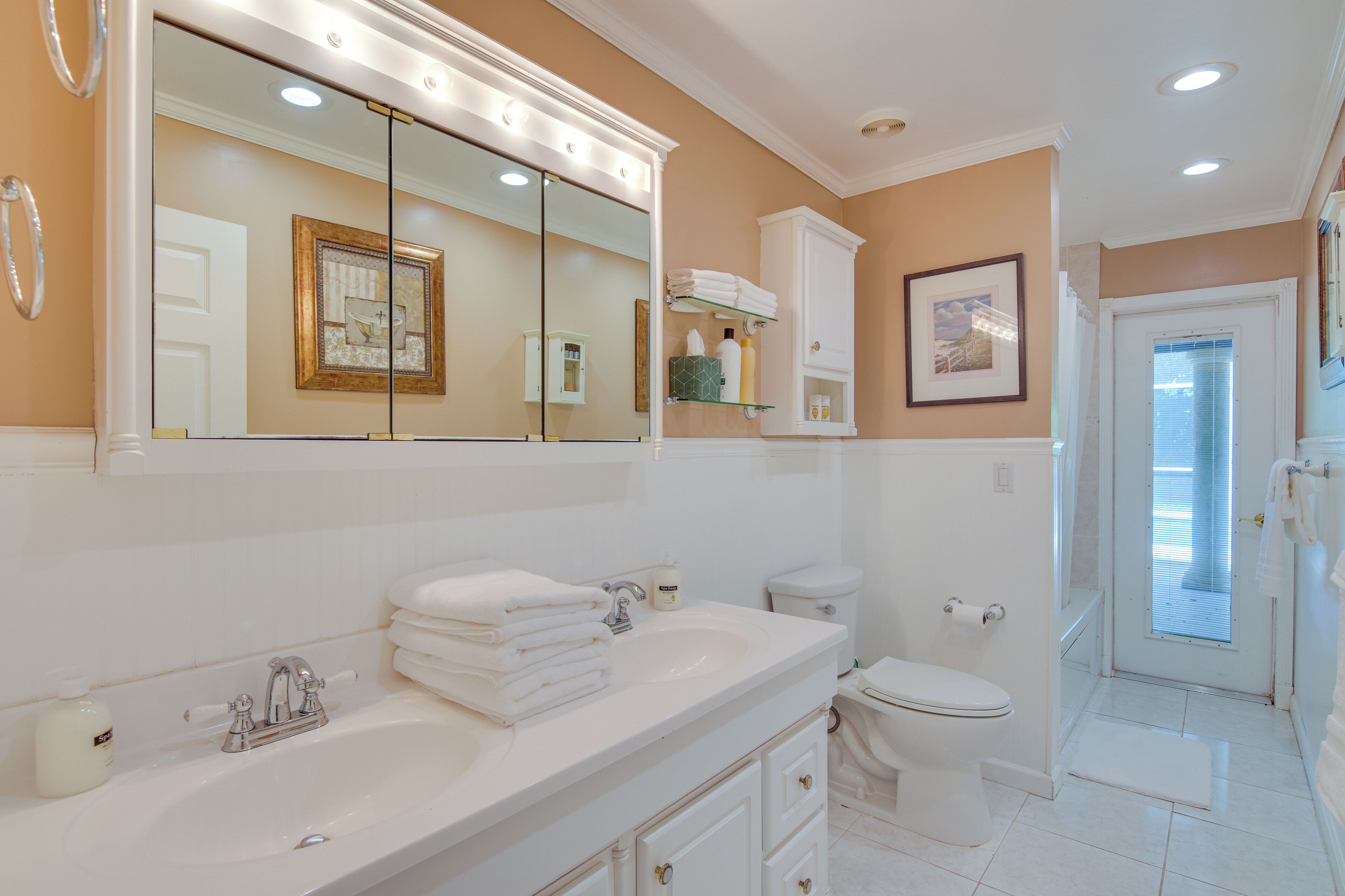 A bathroom with a large mirror, white sink, and toilet.