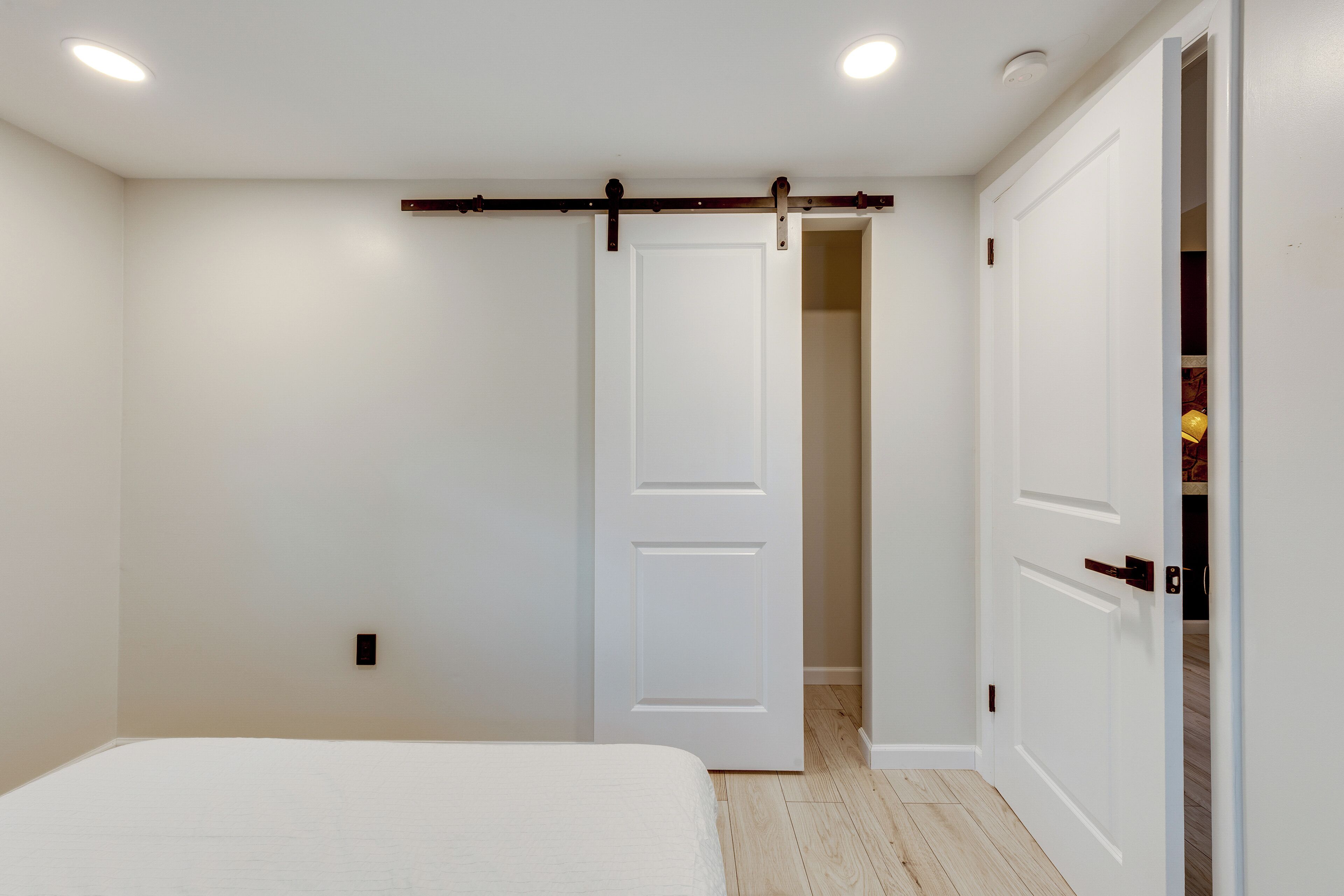 A bedroom with a bed, a white door, and a closet.