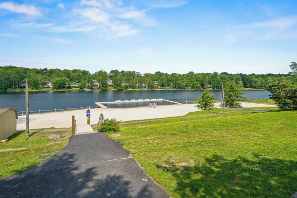 A lakeside view with a dock, grassy areas, and a pathway leading to a building. - Lake Access at Family-Friendly Home in Tobyhanna (Tobyhanna)