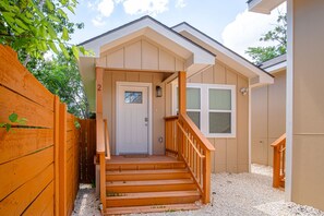 A two-story house with a front porch, a wooden staircase, and a door with a window. - Historic Comfort 2BR 1BA Guesthouse Near Riverwalk (San Antonio)