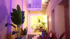 A narrow hallway with a balcony, a seating area with a sofa and armchairs, and potted plants. - Casa Logos Comfort Stay (Cartagena)