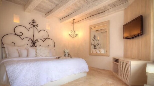 A bedroom with a bed, a bedside table, a mirror, and a wall-mounted TV. - Casa Logos Comfort Stay (Cartagena)