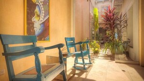A hallway with two blue chairs, a painting on the wall, and potted plants. - Casa Logos Comfort Stay (Cartagena)