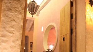 A hallway with a wooden door, a round mirror, and a hanging light fixture. - Casa Logos Comfort Stay (Cartagena)