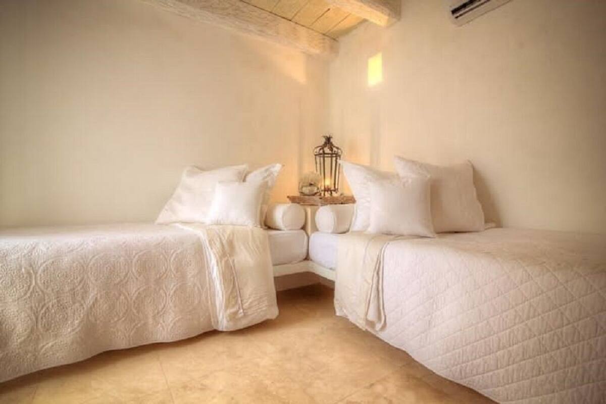 A bedroom with two single beds, a nightstand with a lamp, and a small decorative item on the wall.