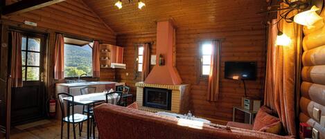 A cozy log cabin interior with a dining area, a fireplace, and a sofa.