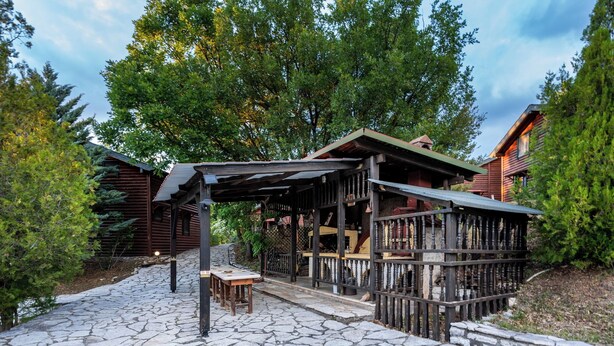 Een rustieke houten chalet met een oprit van stenen en een overdekte veranda.