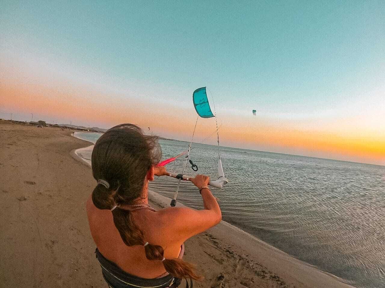 A person standing on a beach holding a kite.