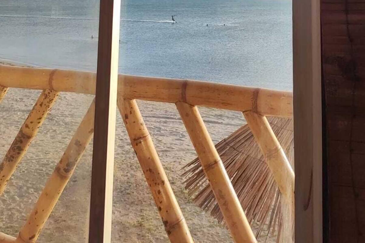 Vista a la playa desde una ventana con marco de madera, con vista al mar.