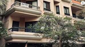 A multi-story building with balconies, a sign for 'Shafik Al-Bish' on the ground floor, and a 'Martello Furnitures' store on the ground level.