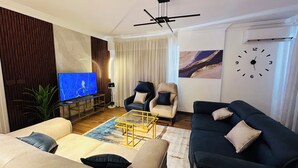 A modern living room with a television, two armchairs, a sofa, and a coffee table.