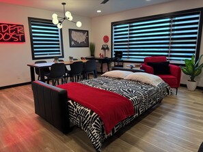 A modern bedroom with a bed, a desk, a chair, and a red armchair.