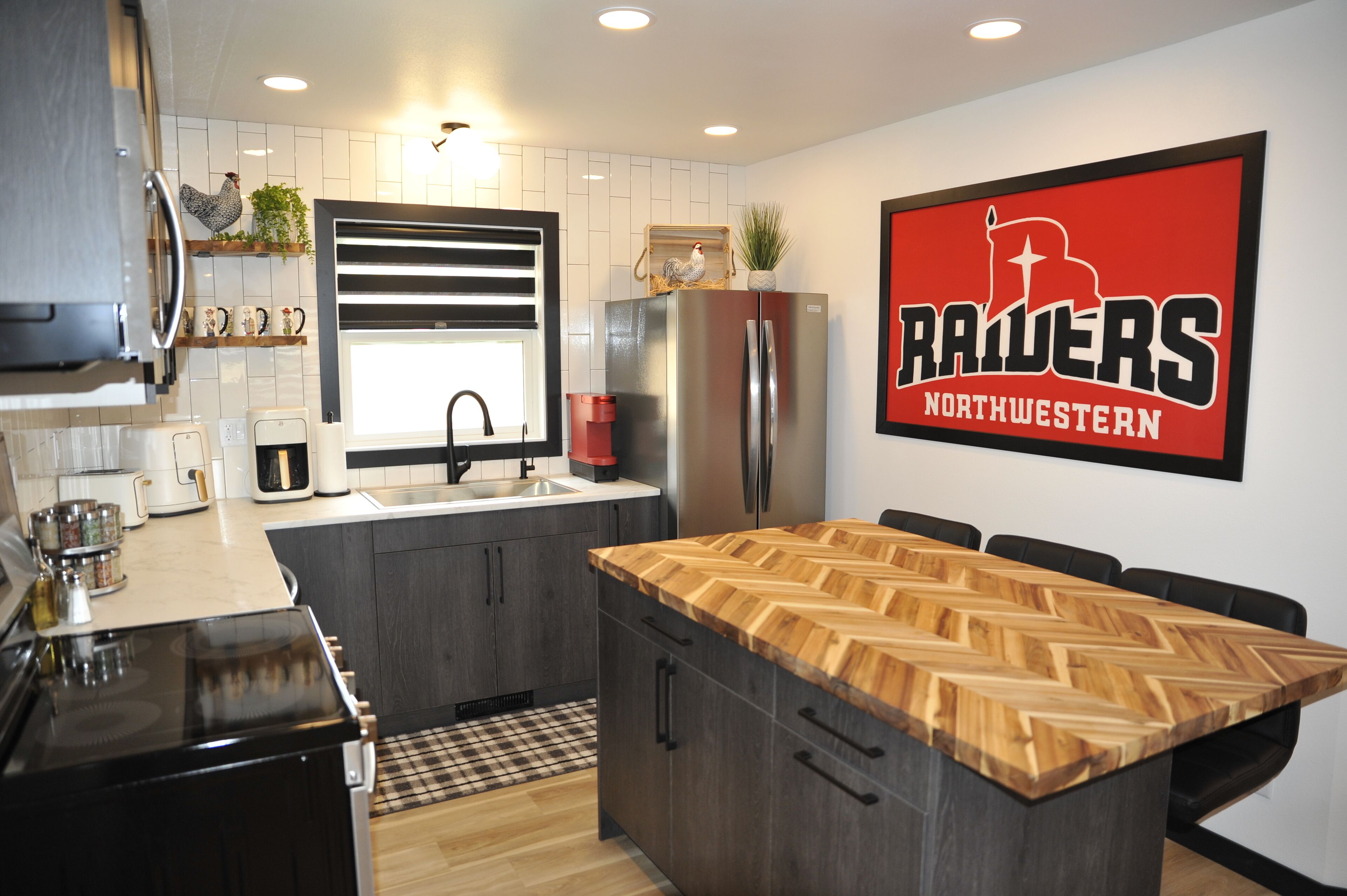 A modern kitchen with a central island, a refrigerator, and a coffee maker.