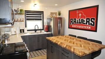A modern kitchen with a central island, a refrigerator, and a coffee maker.