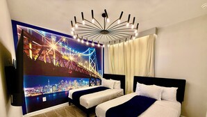 A hotel room with two beds, a large wall mural of a cityscape, a modern chandelier, and a view of the city through the window. - DavenportMagicEscape 8964 (Davenport)