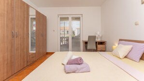 A bedroom with a bed, a desk, a chair, a wardrobe, and a window with blinds. - Stunning apartment in Ugrinic with WiFi (Ugrinic)