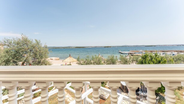 A balcony with a view of a calm sea, boats, and a distant shoreline. - Stunning apartment in Ugrinic with WiFi (Ugrinic)